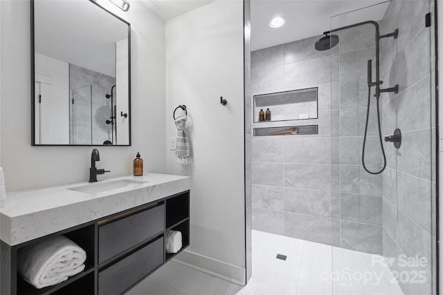 bathroom featuring tiled shower, vanity, and tile patterned flooring