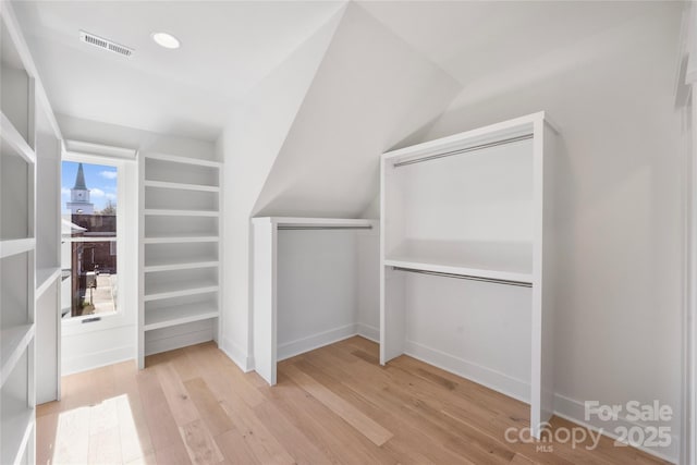 spacious closet featuring vaulted ceiling and light hardwood / wood-style flooring