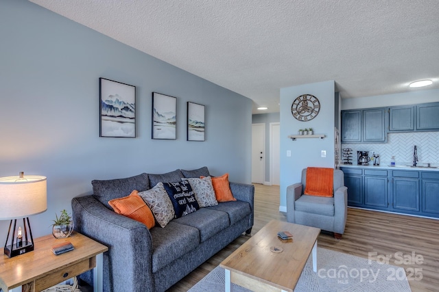 living room featuring a textured ceiling, hardwood / wood-style flooring, and sink