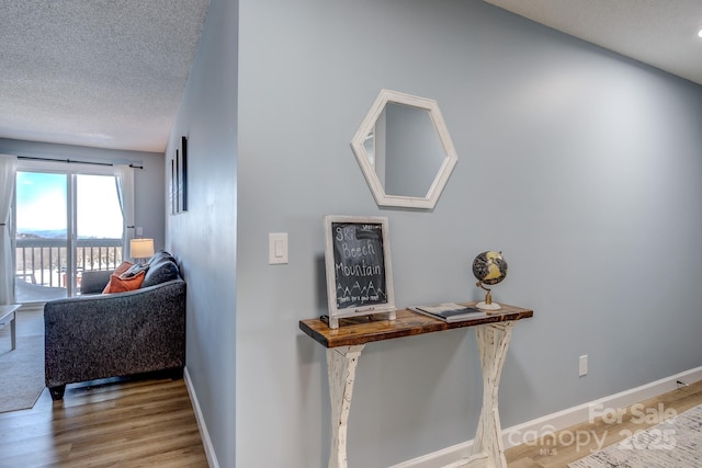 hall with a textured ceiling and light hardwood / wood-style floors