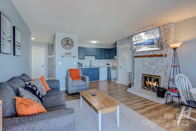 living room with wood-type flooring, sink, a textured ceiling, and a fireplace