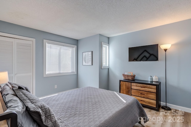 bedroom featuring a textured ceiling and light hardwood / wood-style flooring