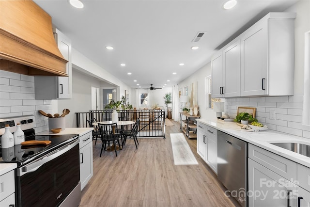 kitchen featuring custom exhaust hood, ceiling fan, appliances with stainless steel finishes, white cabinets, and light stone counters