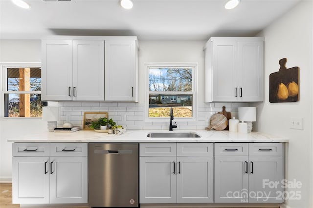 kitchen featuring light stone counters, sink, dishwasher, and tasteful backsplash