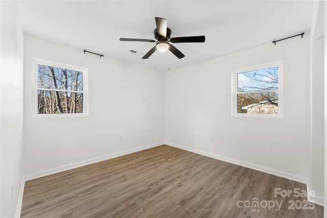 empty room featuring ceiling fan, plenty of natural light, and hardwood / wood-style floors