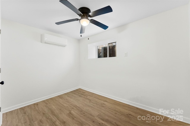 spare room featuring an AC wall unit, wood-type flooring, and ceiling fan