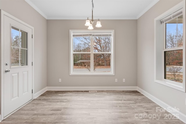 unfurnished dining area with a notable chandelier, ornamental molding, and light hardwood / wood-style floors