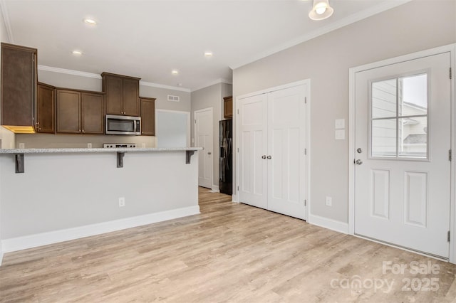 kitchen featuring kitchen peninsula, light hardwood / wood-style flooring, black fridge with ice dispenser, ornamental molding, and a breakfast bar area