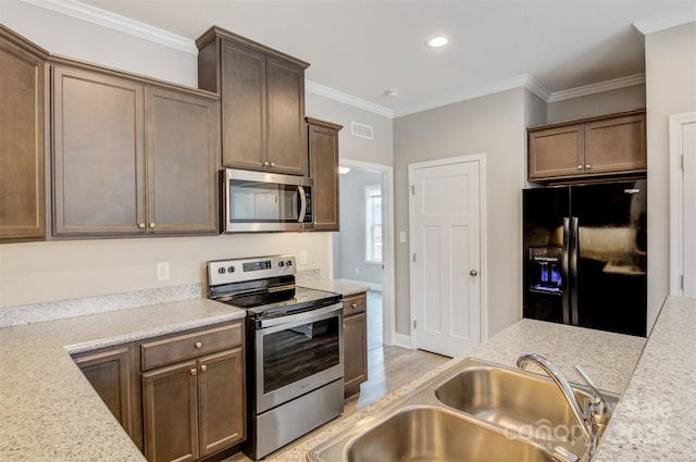 kitchen with sink, light stone counters, crown molding, and appliances with stainless steel finishes