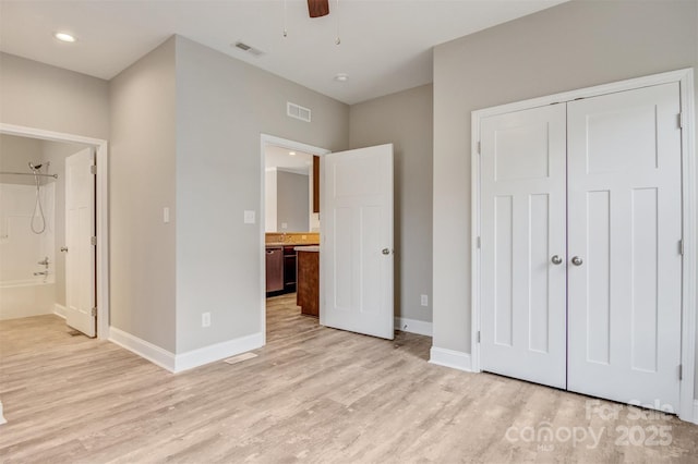 unfurnished bedroom featuring ceiling fan, a closet, ensuite bath, and light wood-type flooring