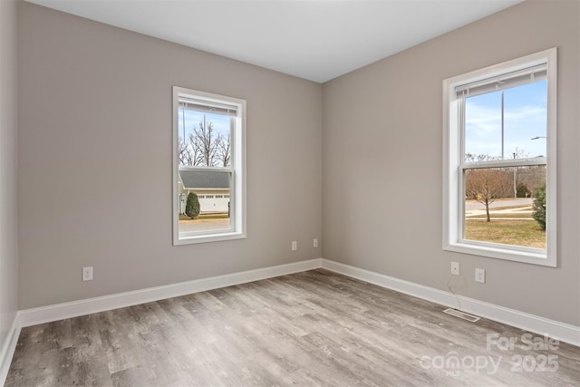 empty room with light hardwood / wood-style floors and plenty of natural light