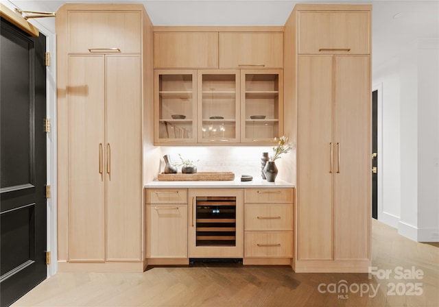 bar featuring wine cooler and light brown cabinetry