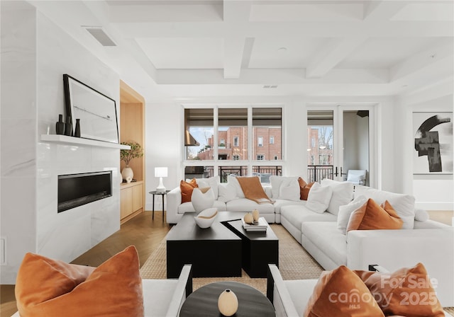 living room featuring hardwood / wood-style flooring, coffered ceiling, beam ceiling, and a tiled fireplace