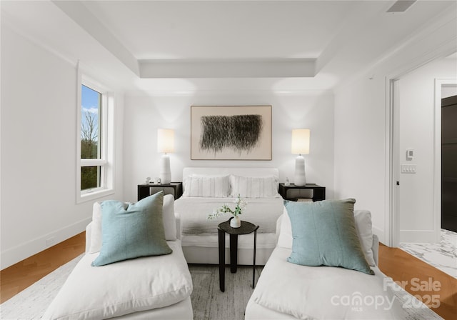 bedroom with a raised ceiling and hardwood / wood-style flooring