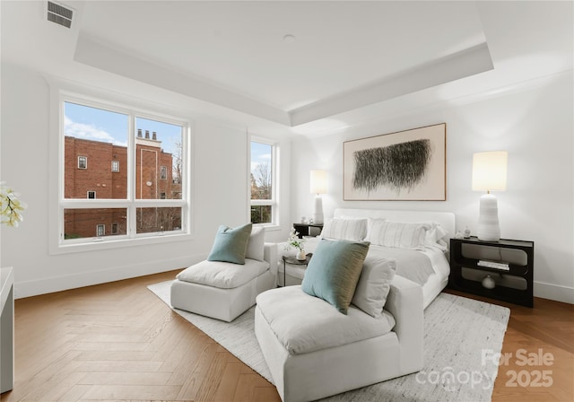 bedroom with a raised ceiling and light parquet floors