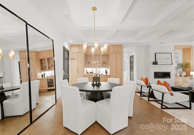 dining room featuring light parquet floors, beverage cooler, a notable chandelier, and coffered ceiling