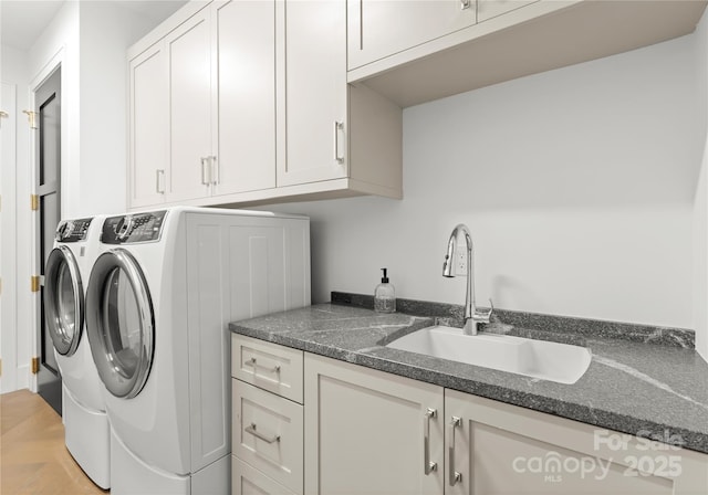 washroom featuring washing machine and dryer, cabinets, and sink