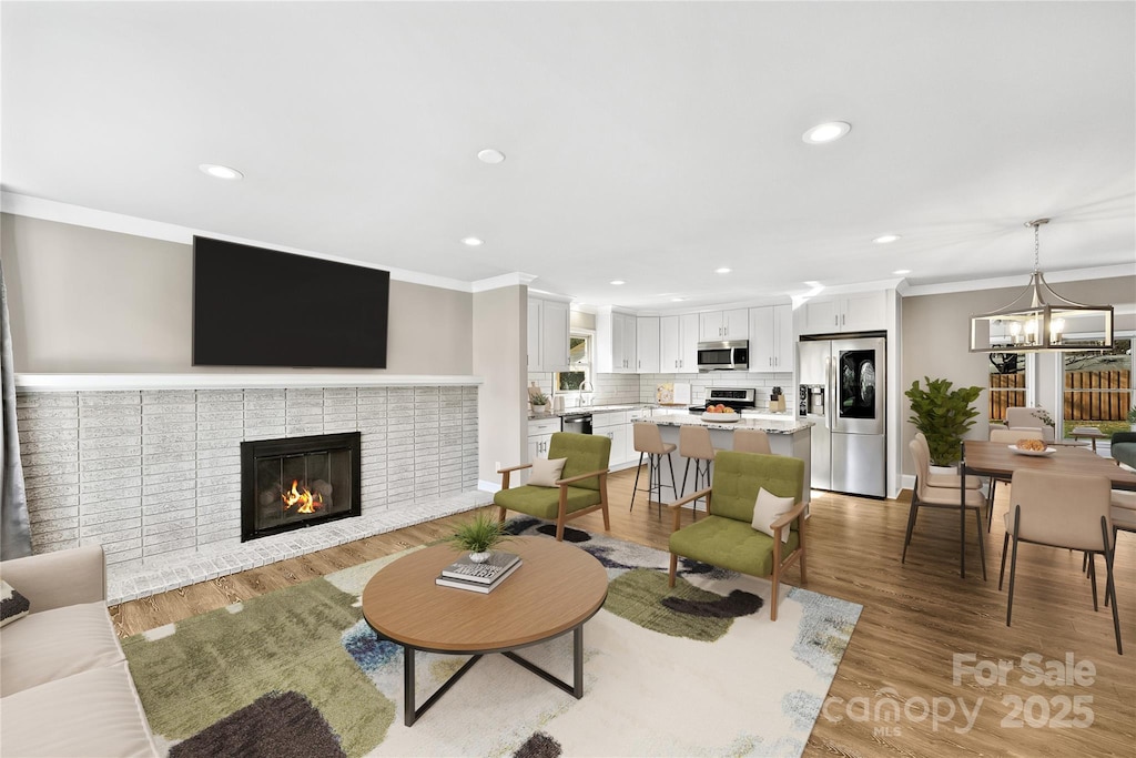 living room with wood-type flooring, a brick fireplace, and ornamental molding