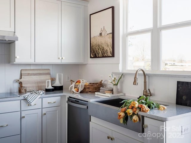 kitchen featuring light countertops, stainless steel dishwasher, white cabinets, a sink, and under cabinet range hood