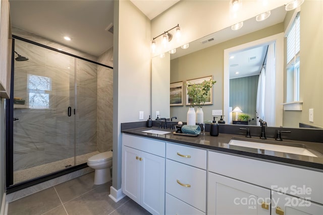 full bathroom with double vanity, a stall shower, visible vents, and a sink