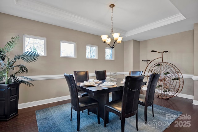 dining area featuring a raised ceiling, a wealth of natural light, an inviting chandelier, dark wood-type flooring, and ornamental molding