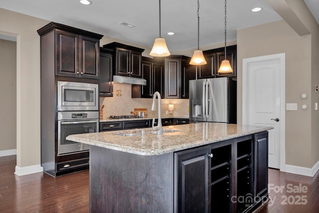 kitchen with decorative light fixtures, sink, stainless steel appliances, and an island with sink