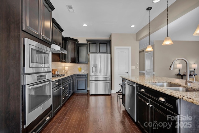 kitchen featuring stainless steel appliances, dark hardwood / wood-style flooring, pendant lighting, light stone counters, and sink