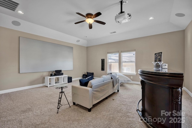 cinema room featuring ceiling fan, light colored carpet, and a tray ceiling