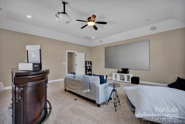 carpeted cinema with ceiling fan and a raised ceiling