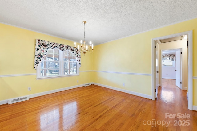 unfurnished dining area featuring a textured ceiling, crown molding, hardwood / wood-style floors, and a notable chandelier