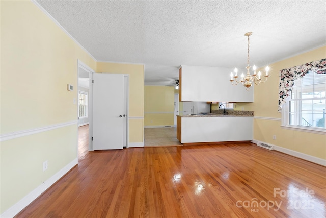 interior space with a textured ceiling, a wealth of natural light, ceiling fan with notable chandelier, and hardwood / wood-style floors