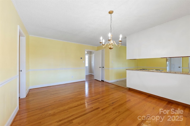 unfurnished room featuring a notable chandelier and light wood-type flooring