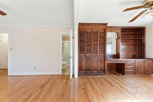 unfurnished bedroom featuring light hardwood / wood-style floors, ceiling fan, crown molding, ensuite bath, and built in desk