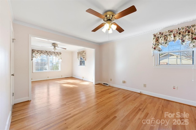 empty room with light wood-type flooring, a wealth of natural light, and ornamental molding