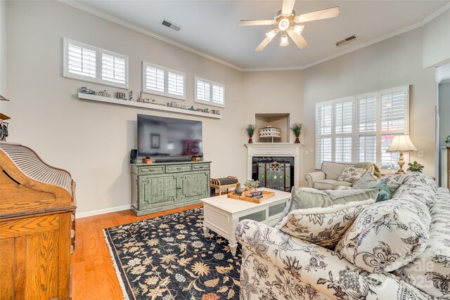 living room featuring ceiling fan, light hardwood / wood-style flooring, and crown molding