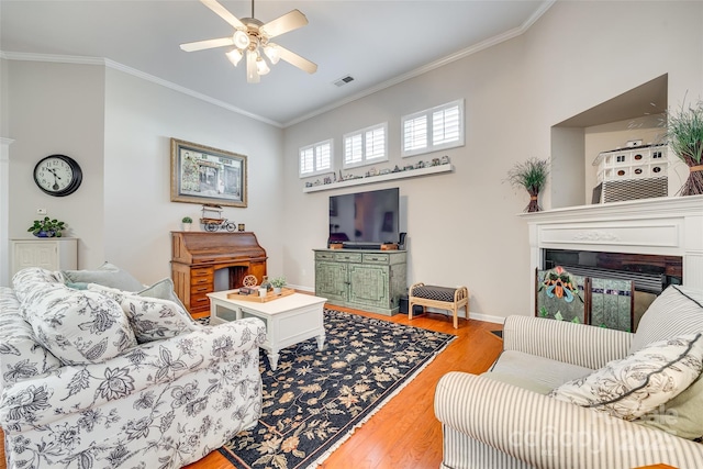 living room with ceiling fan, crown molding, and light wood-type flooring