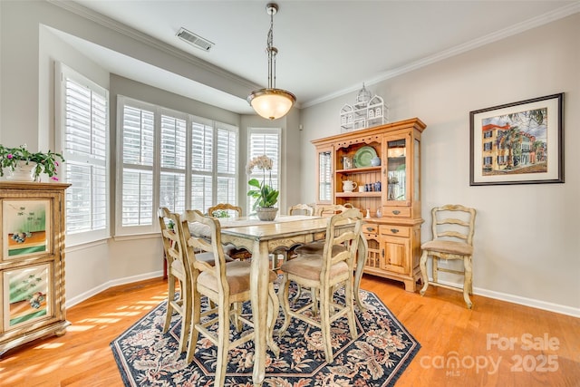 dining space with plenty of natural light, ornamental molding, and light hardwood / wood-style flooring