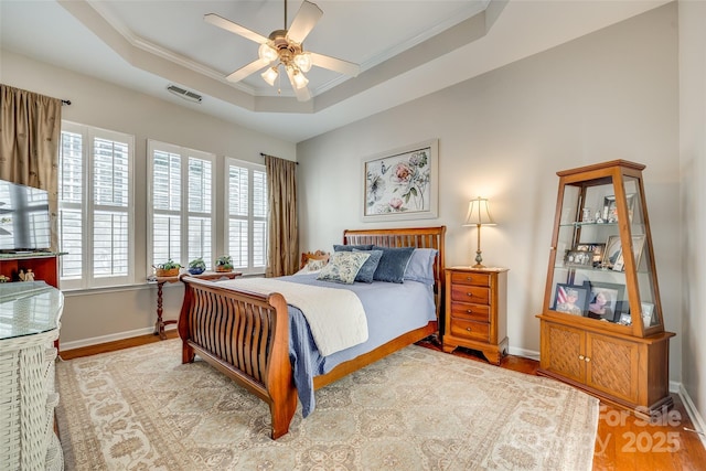 bedroom featuring ceiling fan, a tray ceiling, and light hardwood / wood-style floors