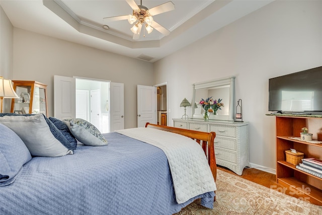 bedroom featuring ceiling fan, crown molding, a tray ceiling, and light hardwood / wood-style flooring