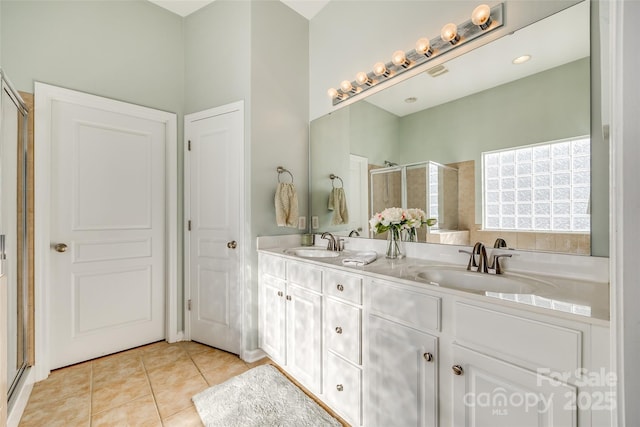 bathroom with a shower with shower door, vanity, and tile patterned flooring