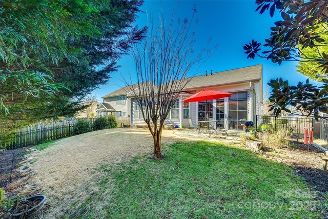 rear view of house with a lawn and a patio