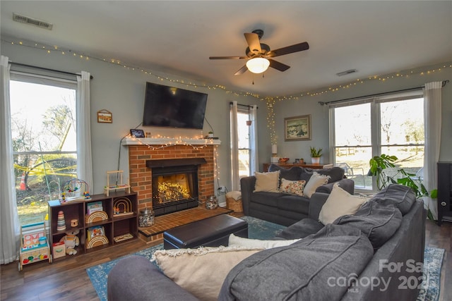 living room with dark wood-type flooring, ceiling fan, a fireplace, and plenty of natural light