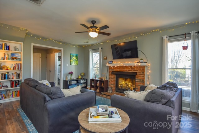 living room featuring a brick fireplace, dark hardwood / wood-style floors, and ceiling fan