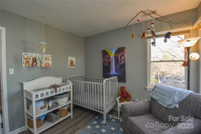 bedroom with wood-type flooring and a nursery area