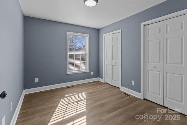 unfurnished bedroom featuring multiple closets and hardwood / wood-style floors