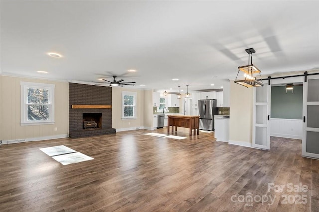 unfurnished living room with a fireplace, a barn door, plenty of natural light, and hardwood / wood-style flooring