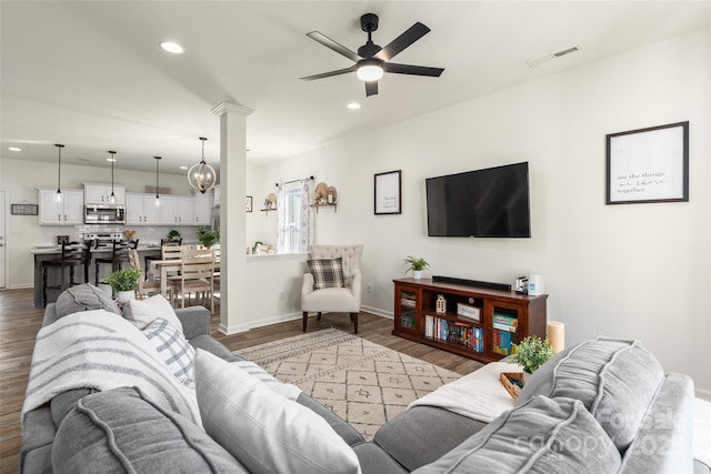 living room with ceiling fan with notable chandelier, hardwood / wood-style floors, and ornate columns