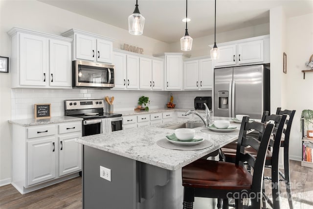 kitchen with stainless steel appliances, an island with sink, sink, and white cabinets