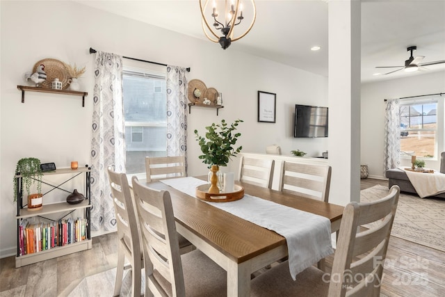 dining space with wood-type flooring and ceiling fan with notable chandelier