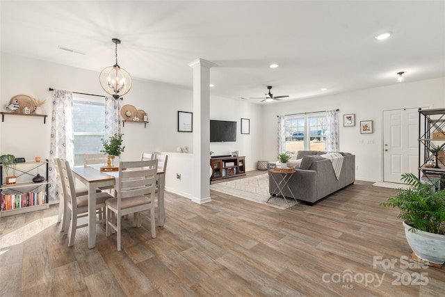 dining area with hardwood / wood-style flooring and ceiling fan with notable chandelier